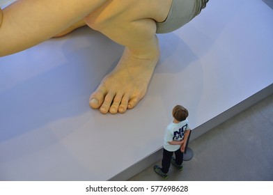 Aarhus, Denmark- May 5, 2016: View Of A Young Child Standing Next To The Sculpture Of Boy By Artist Ron Mueck