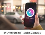 AAVE cryptocurrency symbol, logo. Business and financial concept. Hand with smartphone, screen with crypto icon close-up