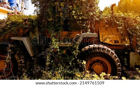 An abandoned agricultural tractor is covered with vegetation