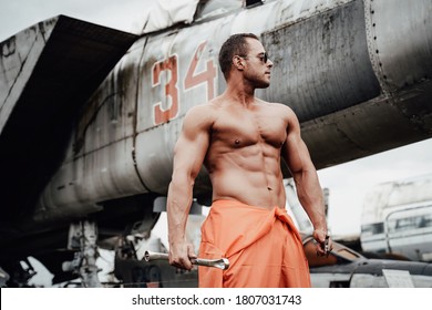 Abandoned Airport And Crashed Old Airplanes With Strong Bodybuilder With Huge Biceps. Fashionable Mechanic Staying Near Old Military Aircraft.