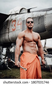 Abandoned Airport And Crashed Old Airplanes With Strong Bodybuilder With Huge Biceps. Fashionable Mechanic Staying Near Old Military Aircraft.