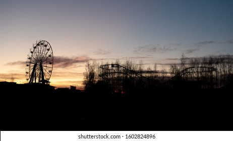 Abandoned Amusement Park With Carousel And Roller-coaster, After Sunset.