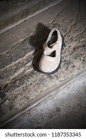Abandoned baby shoe lying on old concrete floor. Lost children's shoes.