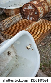 Abandoned Bathtubs, Rusted Metal Radiators And Rusted 50 Gallon Drum Outdoors On The Ground