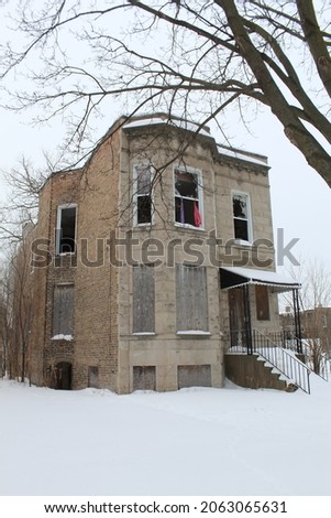 Abandoned and boarded-up graystone two flat in Englewood in snow in Chicago's South Side Englewood neighborhood