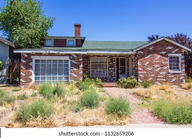 Abandoned Brick Home With Overgrown Front Yard