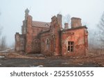 Abandoned brick house with a decayed wall and broken window in a misty rural area