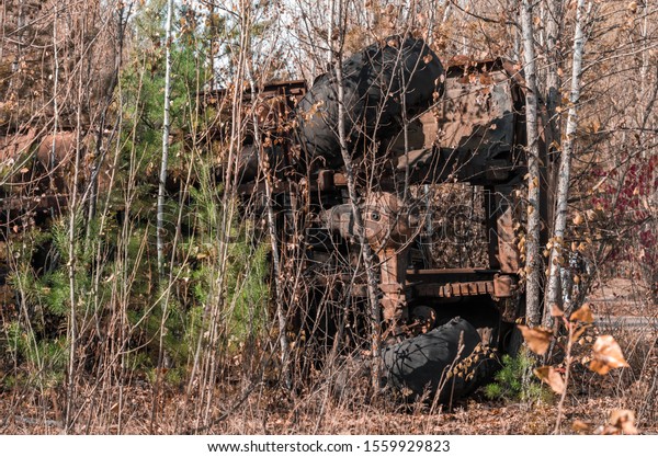 abandoned broken equipment car in the Chernobyl\
forest Ukraine in\
autumn