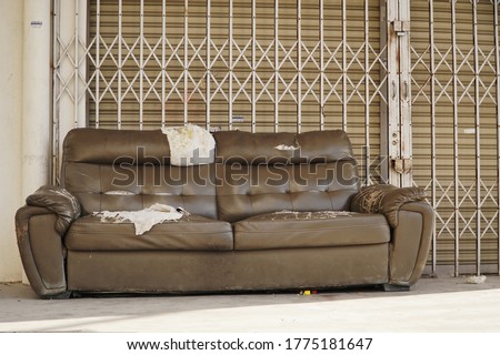 Abandoned broken sofa in front of shop                 