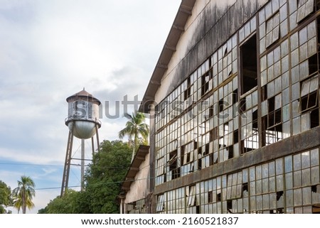 Abandoned building with broken windows and historic water tank tower of Fordlandia city village in Amazon rainforest, Brazil. Town built by Henry Ford in 1928.	