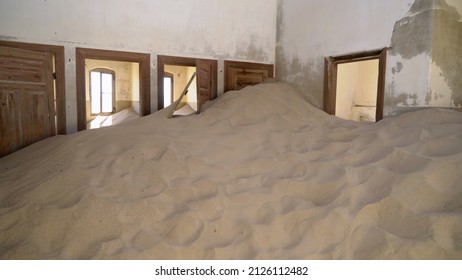 Abandoned building in ghost town Kolmanskop in desert. Room in house filled with sand in ruined house indoors. Nobody in a city, floor covered with sand. 