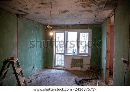 Abandoned building interior in disrepair with debris, exposed pipes, and missing doors awaiting renovation