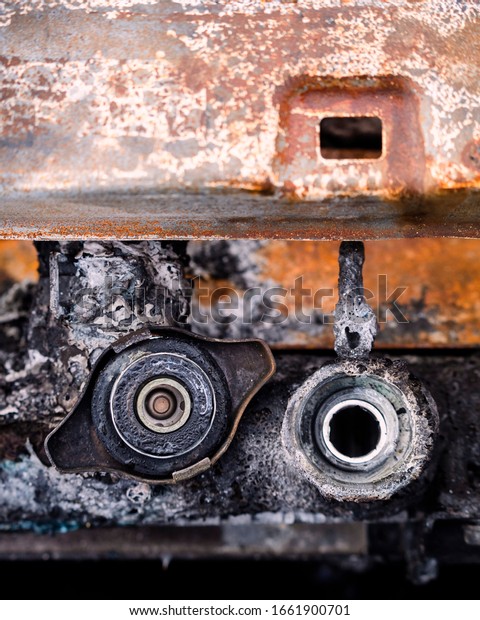 Abandoned and burnt\
stolen car radiator with cap lid and fire soot rust and corrosion\
looks old vintage\
grunge