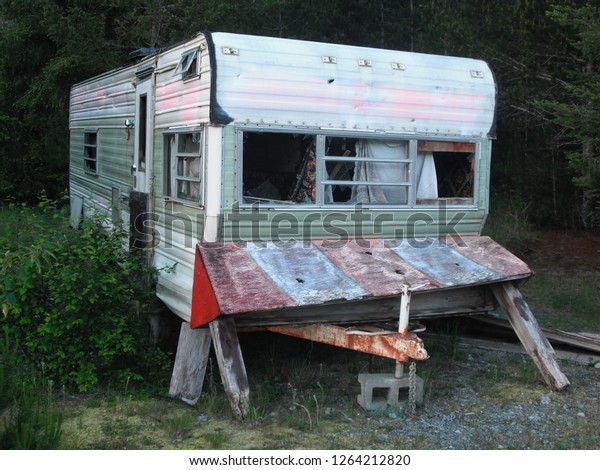 Abandoned camping trailer left behind in the deep woods on Vancouver Island in British Columbia. The interior is messy, windows are missing and nobody is living inside or using it for any purpose.