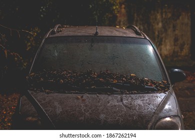 Abandoned Car At Night With Autumn Leaves Over The Bodywork