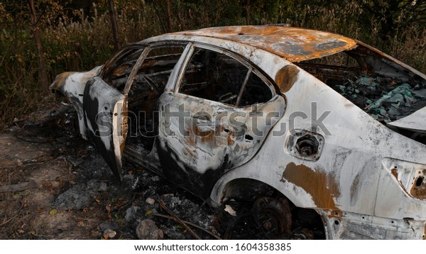 Abandoned car.\
Passenger car after a strong fire. Arson of a car near the city.\
Burnt interior and car body. The concept of a traffic accident and\
vandalism or crime. 