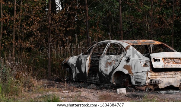 Abandoned car.\
Passenger car after a strong fire. Place next to a burnt car. A lot\
of rubbish, singing and metal parts. The concept of a traffic\
accident and vandalism or crime.\
4k