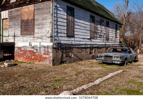 An abandoned car rests\
outside of an equally derelict house in the river town of Cairo,\
Illinois.