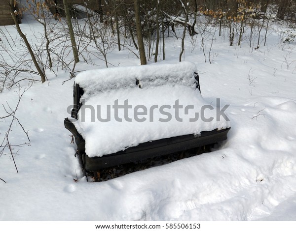 Abandoned\
car seat left in the woods, covered with snow.\
