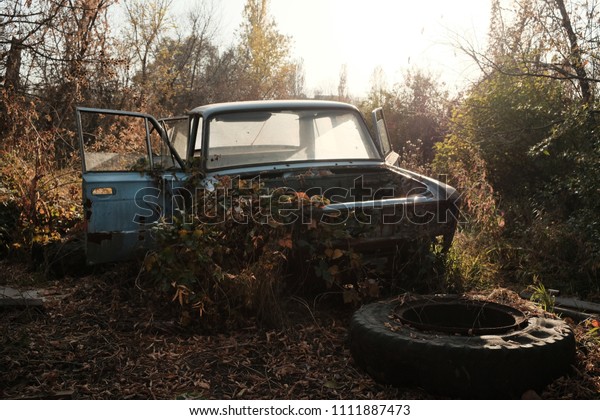 Abandoned car wreck in forest. Old rusted car\
abandonned in the\
woods.