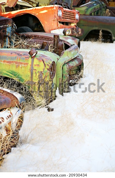 abandoned cars in the snow\
at a junkyard
