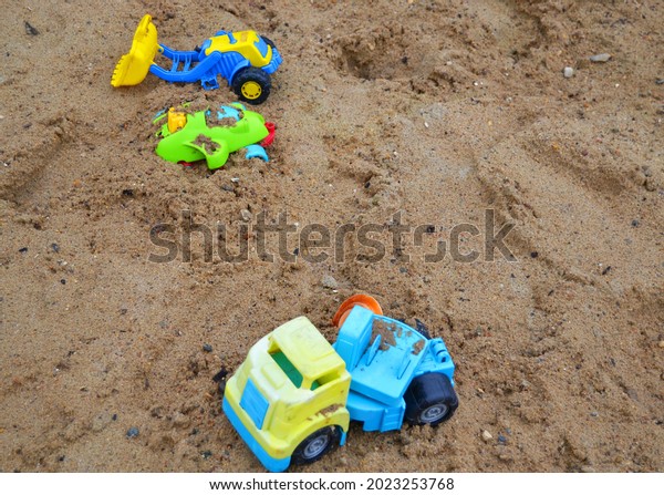 an abandoned children\'s toy truck inside a\
sand pit, a children\'s\
playground.