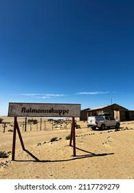 Abandoned City Of Kolmanskop In Namibia. Ancient City Covered With Sand In The Desert Of Africa. Diamond Mine. Ghost Town. Road Sign Kolmannskuppe. SUV Car.