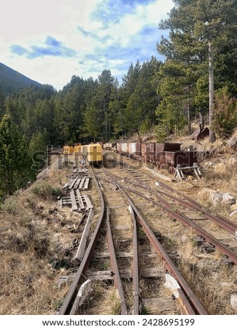 Abandoned coal mine with rusty minecarts and railroad in a mountain forest
