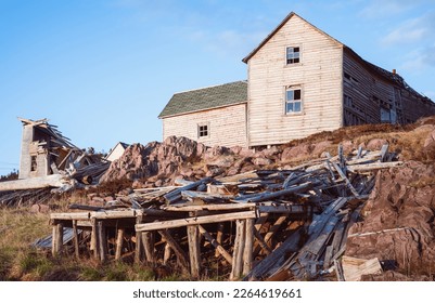 Abandoned, collapsing fishing stage and traditional house in Red Cliff, Newfoundland near Bonavista. Old timber rotting and falling apart, a derelict house crumbles in on itself in the corner.  - Shutterstock ID 2264619661