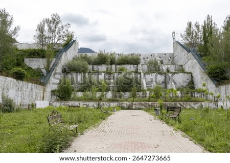 Abandoned dam with overgrown vegetation and empty benches