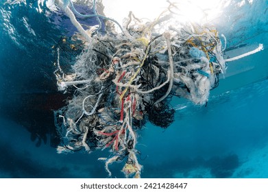 Abandoned debris fishing net or ghost net and plastic garbages in the sea. Clean up the ocean by collecting waste. Save the ocean and underwater world from trash pollution. Environmental conservation