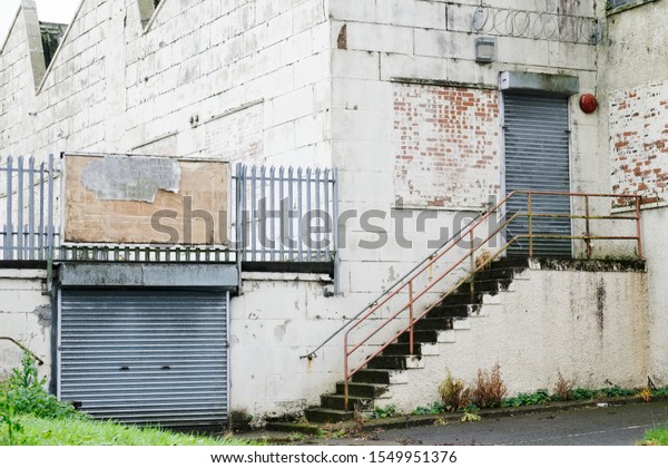 Abandoned derelict business metal roller shutter closed\
at door and garage 