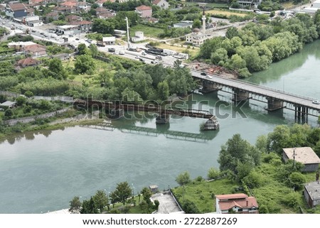 Abandoned and destroyed bridge and a functioning bridge over the Drin River next to a mosque in Shkodër, Albania during a day of spring.