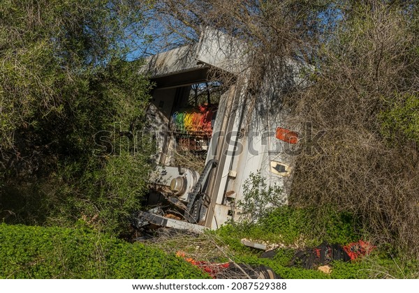 Abandoned and disused industrial car wash machine\
in a Mediterranean forest on a sunny day. Image of incivism\
throwing waste in\
nature