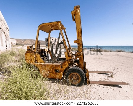 Abandoned equipment with the elements taking over. Natural earth recouping its land as the manmade objects deteriorate. Rusting and crumbling back into dirt. Abandoned by a shut down business and left