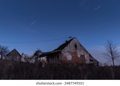 Abandoned farm house against starry night sky, night landscape with star trails in long exposure - Powered by Shutterstock