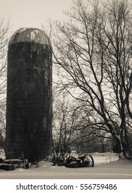 Abandoned Farm In Winter  In Taylors Falls, Minnesota. Silo And Broken Farm Equipment In Black And White Cream Tone.