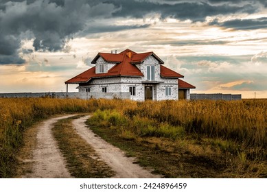 Abandoned farmhouse with red roof in the field at sunset under stormy clouds. Rural road. Beautiful landscape - Powered by Shutterstock