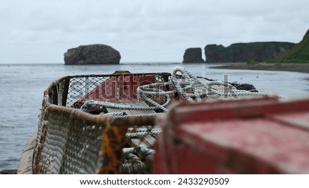 Abandoned fishing boat on background of rocky coast. Clip. Fishing boat with net on seashore with view of rocks. Abandoned fishing boat stands on shore of rocky coast of sea