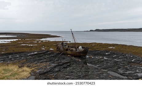 Abandoned fishing boat stranded on rocky shore during low tide near coastal landscape
 - Powered by Shutterstock