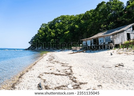 An abandoned fishing house on the seashore. Wooden house on the seashore. Fishing house on the seashore on a sunny summer day. Selective focus.