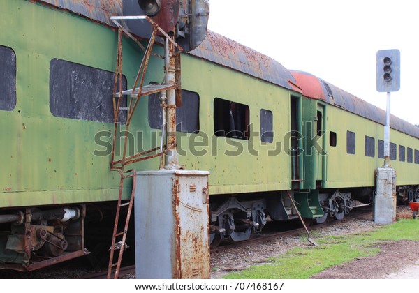 Abandoned\
green train boxcars alongside train light\
posts