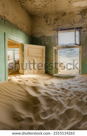 Abandoned house being taken over by  sand in the Kolmanskop ghost town near Luderitz, Namib Desert, Namibia.