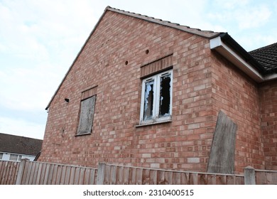 Abandoned house with a boarded up window and a smashed window UK