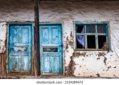 An Abandoned House , An Old Blue Door Split In Half By A Wooden Column , Curtain Appearing On A Window Standing By The Textured Door , 