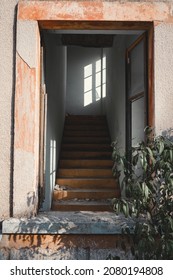 Abandoned House With A Smashed Window And A Staircase Leading To A Possible Second Floor.