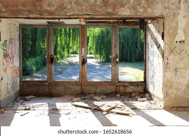 An Abandoned Interior, View From Inside Looking Out, Sunbeam Shines Through Young Green Park And Ruined Window Into An Old  Wall. Focus On Wall.