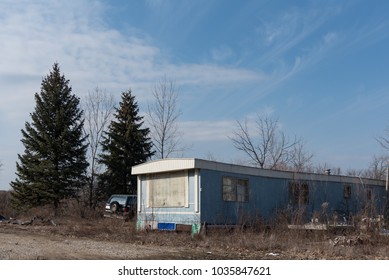 Abandoned mobile home on a vacant property with junk car next to it. Taken in Lake County, IL on Febr. 28, 2018