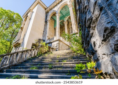 Abandoned neoclassical building with grand staircase overgrown with vegetation, architectural decay and urban exploration. Majestic stone columns and cracked facade - Powered by Shutterstock