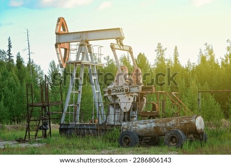 An abandoned oil or gas rocking machine against a blue sky, exhausted resource. A clogged field of gas and oil production.